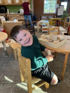 Lake Superior Academy student smiling at the camera from their chair as they work with Montessori Resources.